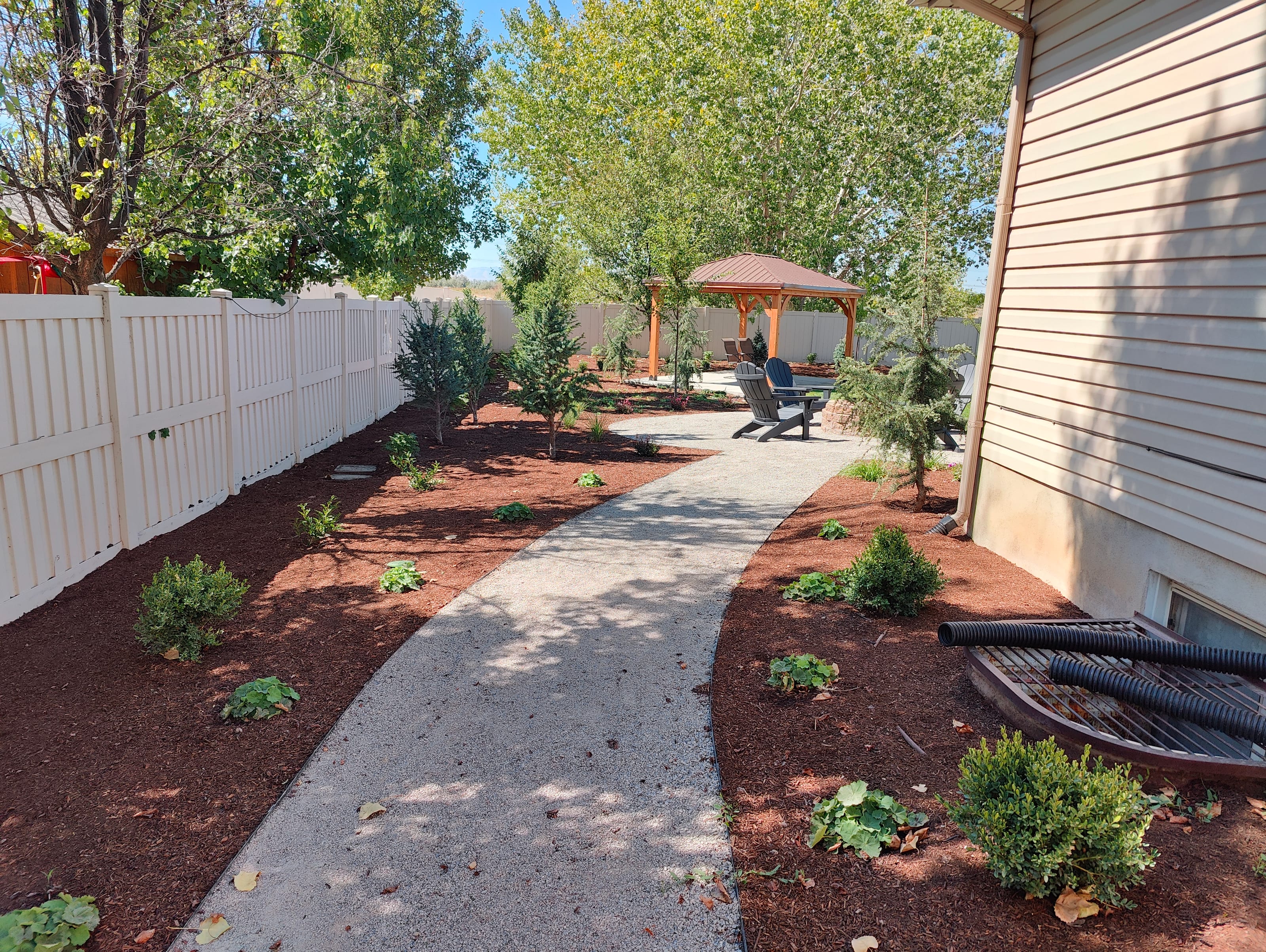 Utah side yard rock landscaping with pebble walkway, mulch beds, and low-water plants